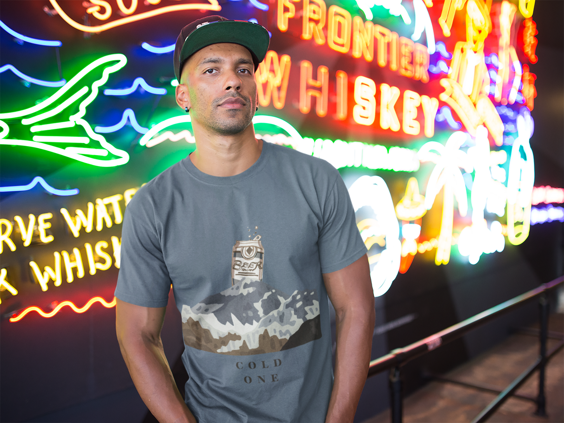 Man wearing a gray t-shirt with a graphic design in front of neon signs.
