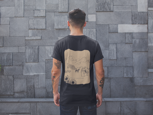 Person wearing a black t-shirt with a graphic design on the back against a gray tiled wall.