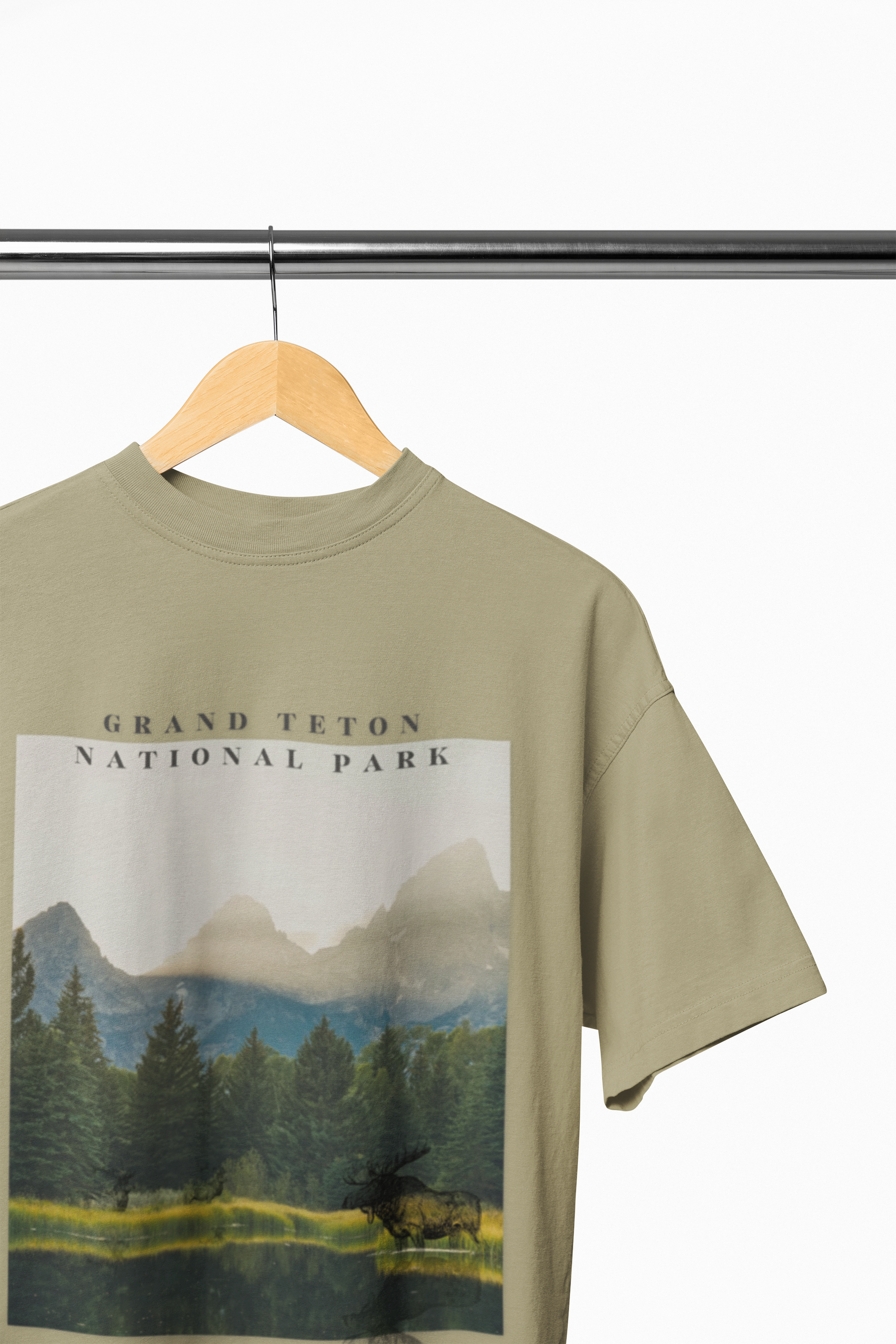 Olive green t-shirt with Grand Teton National Park graphic on a hanger against a white background