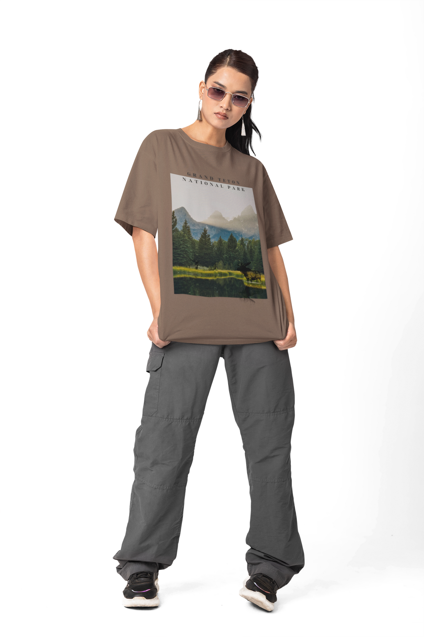 Person wearing a brown t-shirt with a nature graphic and gray pants on a white background