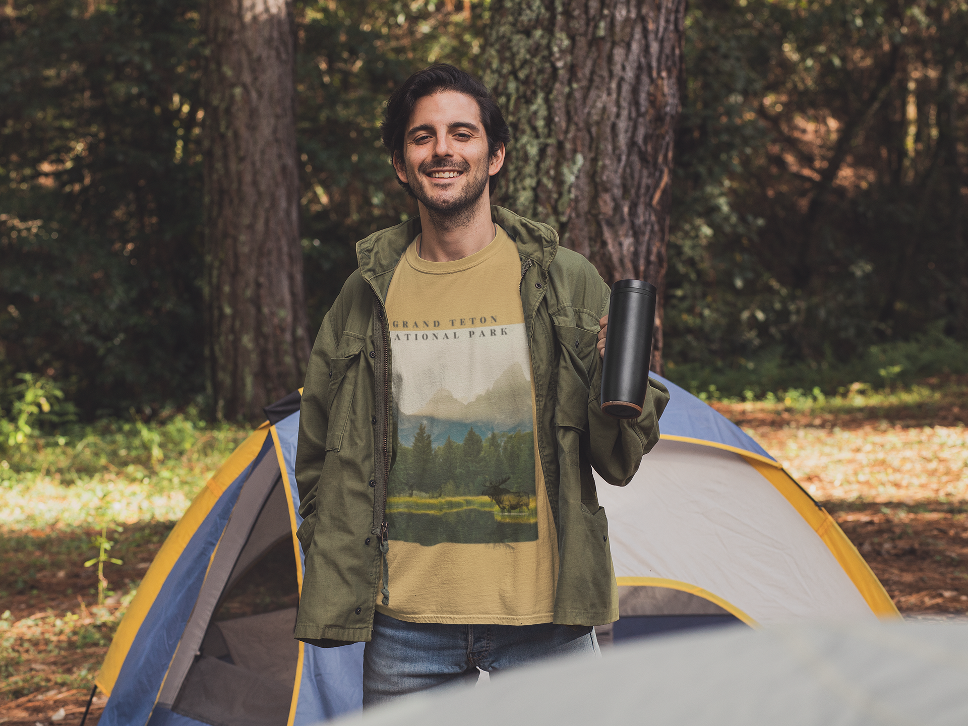 Man standing next to a tent in a forested area