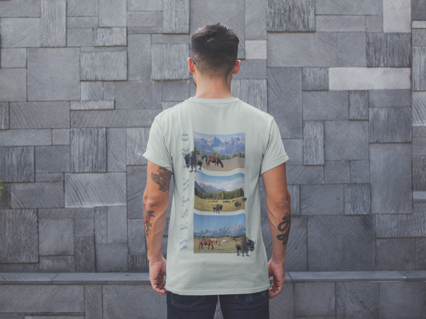 Person wearing a t-shirt with a nature-themed graphic on the back, standing against a stone wall.