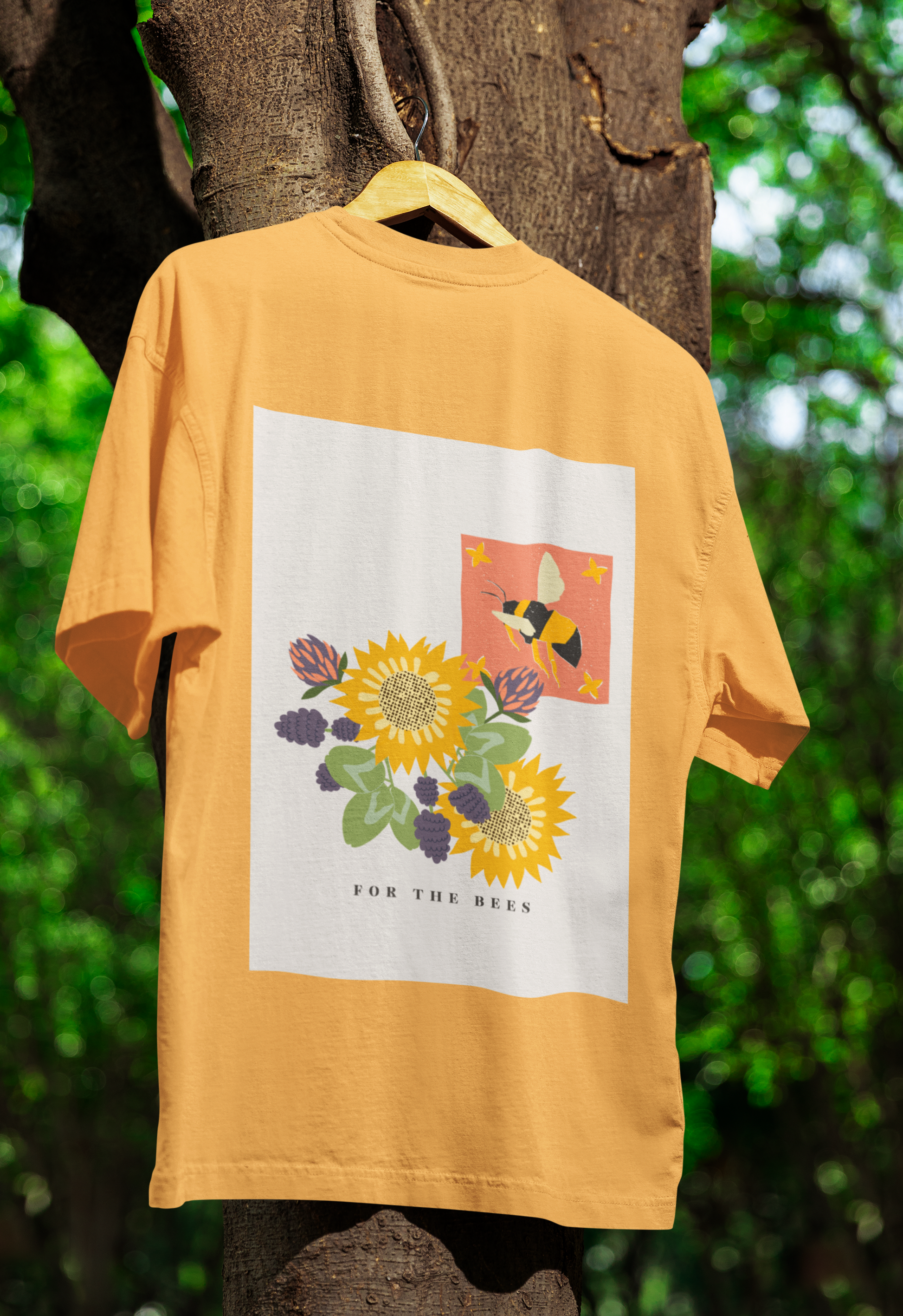 Yellow t-shirt with floral design and text hanging on a tree branch